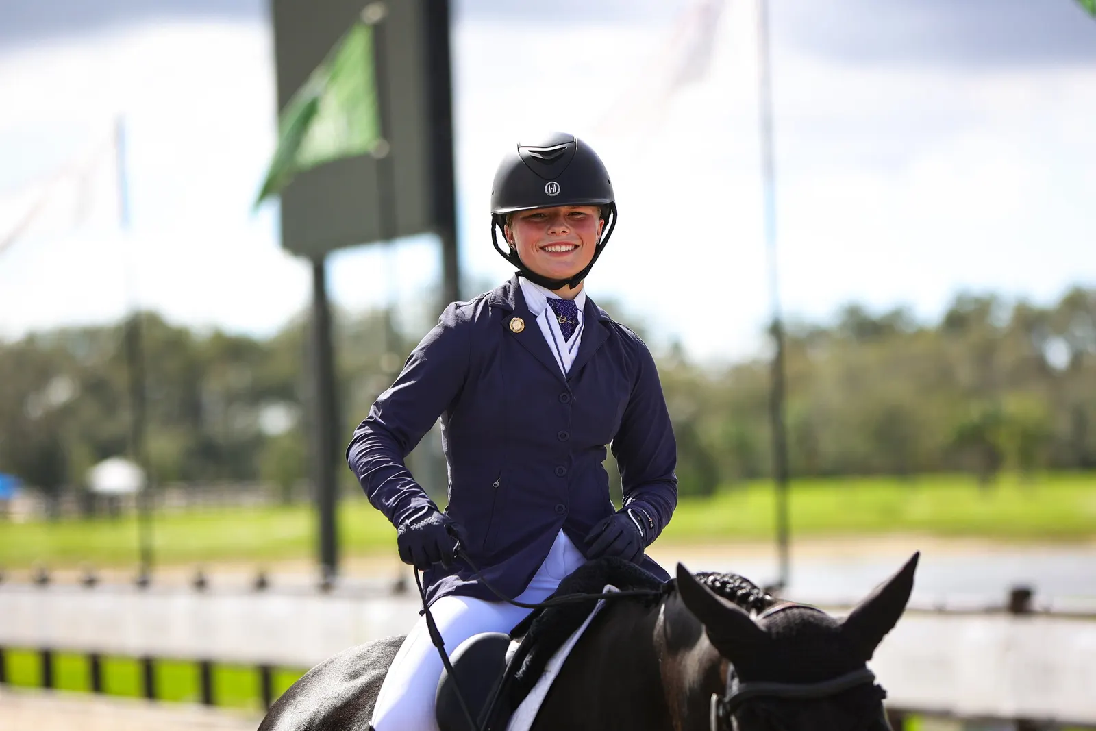 Smiling young rider in navy show coat aboard a dark horse after a dressage test at The Event at TerraNova. Photo by EQ Media.