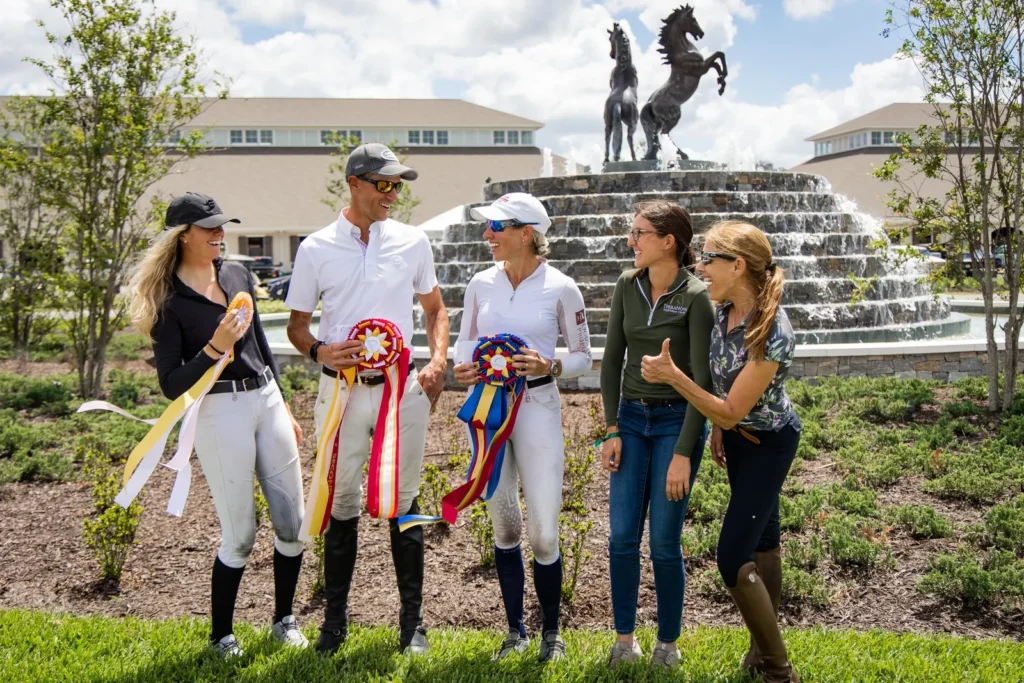 Smiling riders holding prize ribbons in front of the horse statue fountain at The Event at TerraNova Spring 2023. Photo by EQ Media.
