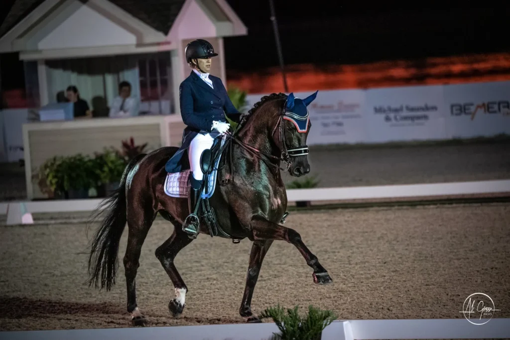 Lehua Custer riding a dark bay horse in a CDI dressage test under the lights at TerraNova Equestrian Center. Photo by Al Green.