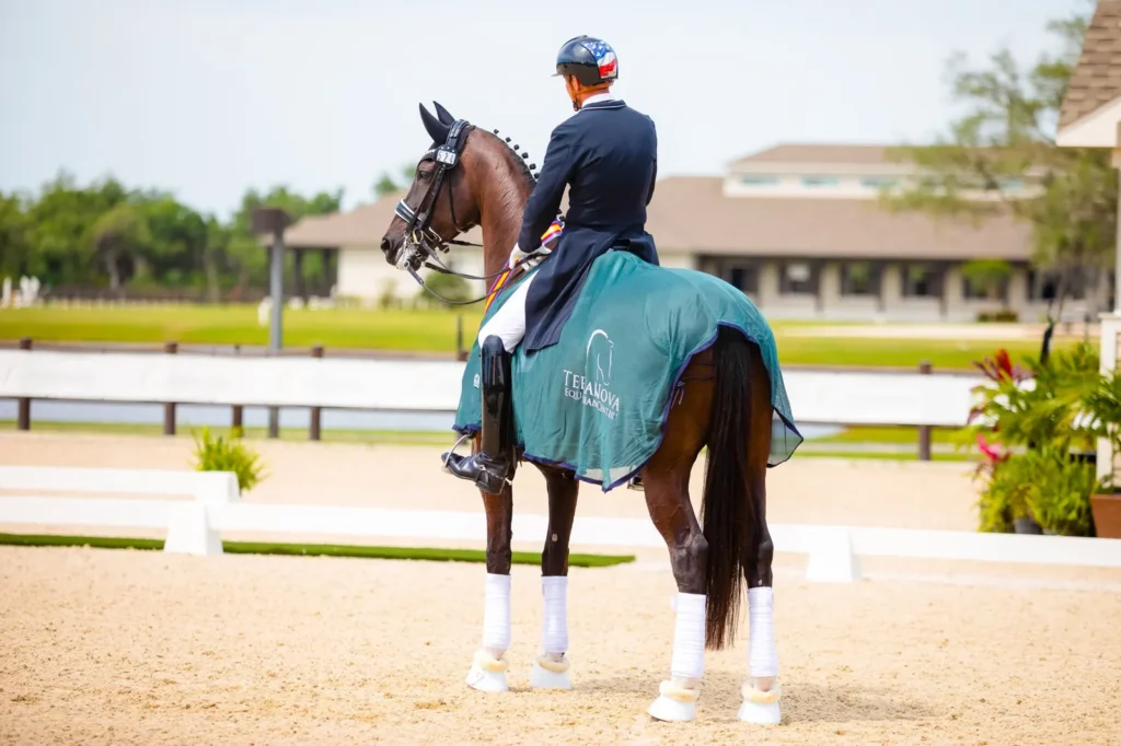 Marcus Orlob aboard Jane wearing a green TerraNova Equestrian Center cooler and winner's ribbons in the dressage arena. Photo by Jessica Buehler Photography.