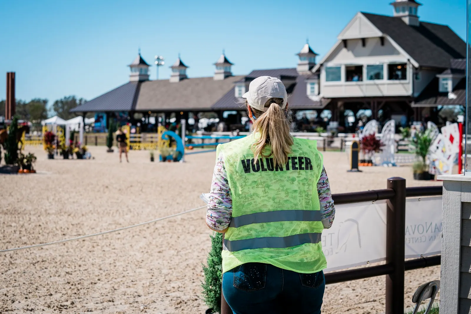 A volunteer in a yellow safety vest watching the show jumping arena and pavilion at TerraNova Equestrian Center. Photo by EQ Media.