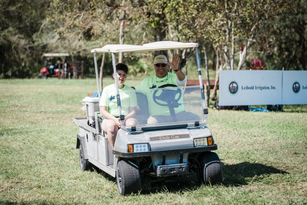 Volunteers riding a golf cart on the cross-country course at TerraNova